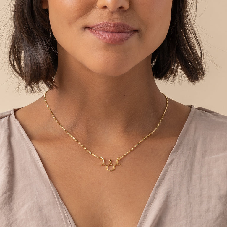 Close-up of woman wearing propofol necklace in gold vermeil – unique science-inspired jewelry with molecular design. Close-up of woman wearing propofol necklace in gold vermeil – unique science-inspired jewelry with molecular design.