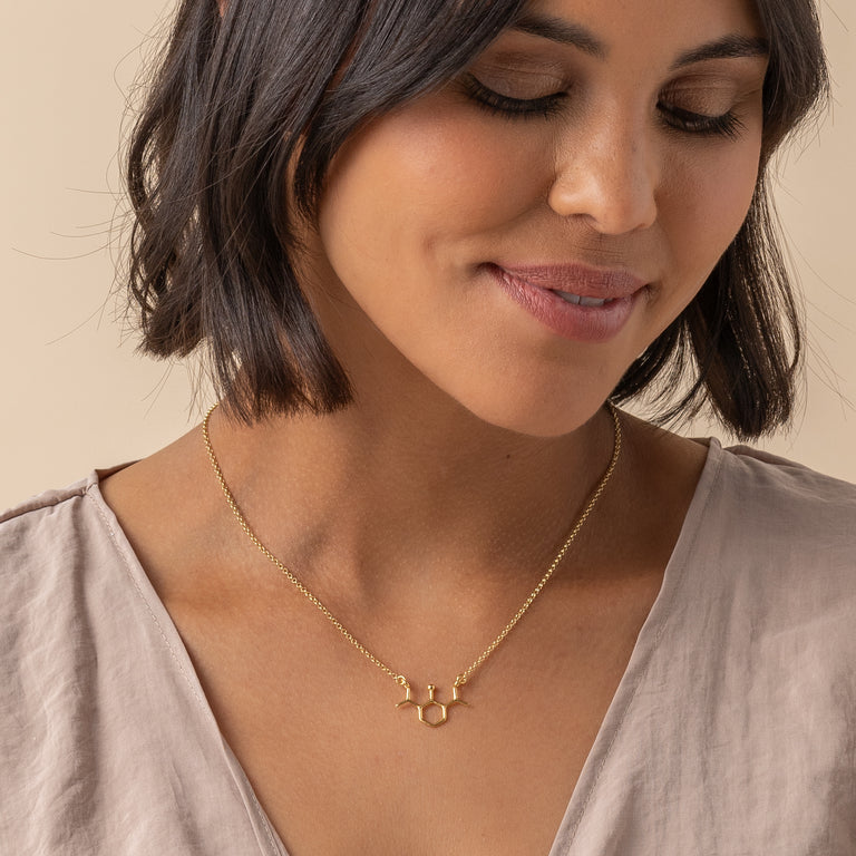 Science jewelry featuring propofol molecule in gold vermeil on model – stylish gift for doctors and med school grads. Science jewelry featuring propofol molecule in gold vermeil on model – stylish gift for doctors and med school grads.
