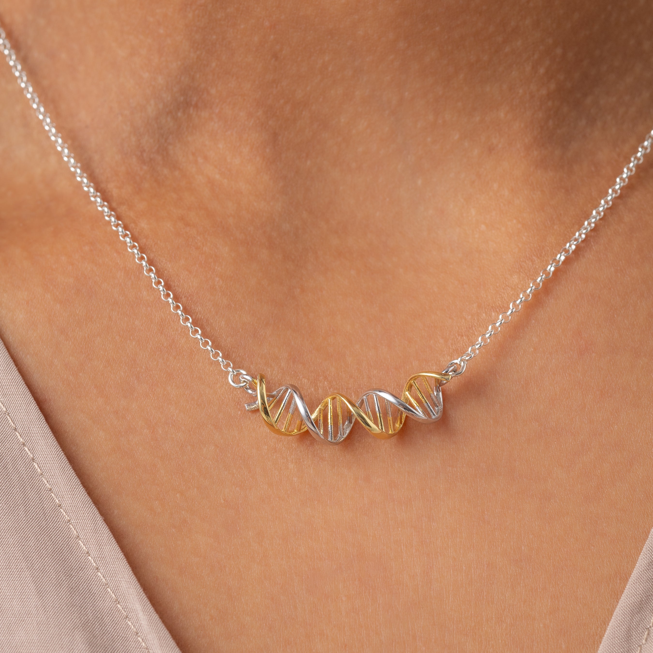 Close-up of a model wearing the two-tone silver and gold DNA necklace, perfect for science enthusiasts and lovers of unique jewelry. Close-up of a model wearing the two-tone silver and gold DNA necklace, perfect for science enthusiasts and lovers of unique jewelry.