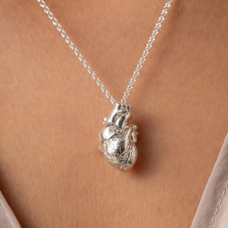 Anatomical Heart Necklace worn by a model, showcasing the detailed design and silver finish. Anatomical Heart Necklace worn by a model, showcasing the detailed design and silver finish.