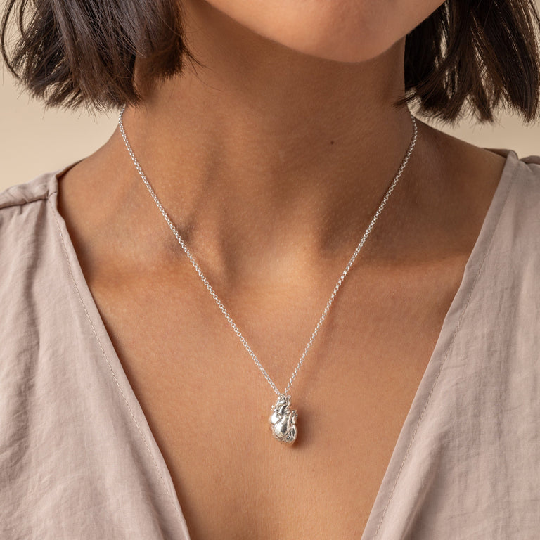 Close-up of the Anatomical Heart Necklace being held, showing the detailed craftsmanship. Close-up of the Anatomical Heart Necklace being held, showing the detailed craftsmanship.