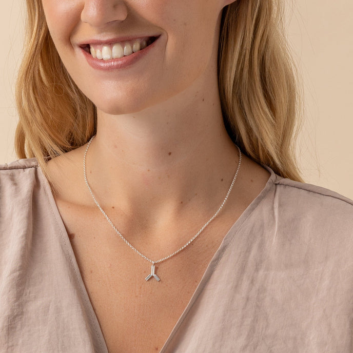 Woman wearing silver antibody necklace, a unique science-inspired accessory. Woman wearing silver antibody necklace, a unique science-inspired accessory.