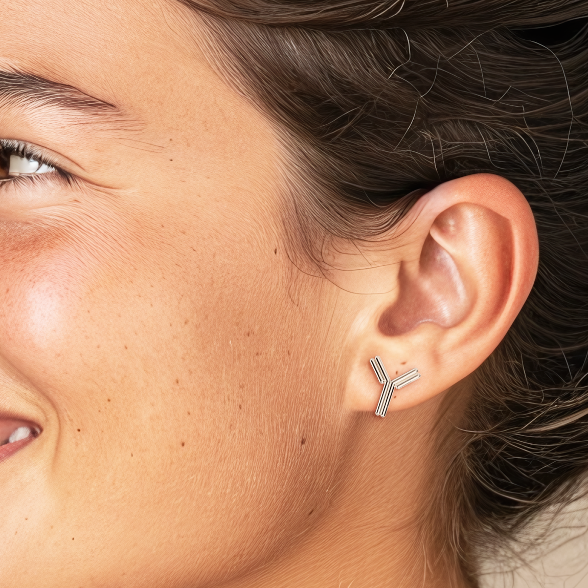 Woman wearing antibody stud earrings on earlobe – stylish and subtle science-inspired accessory. Woman wearing antibody stud earrings on earlobe – stylish and subtle science-inspired accessory.