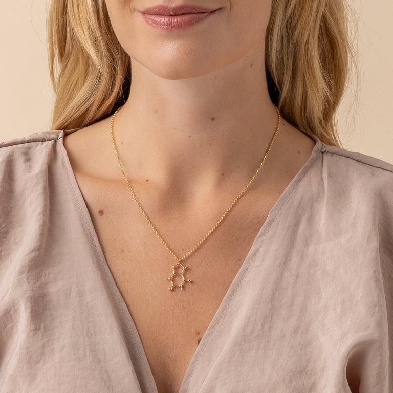 Close-up of gold vermeil caffeine molecule necklace on model – perfect gift for coffee addicts. Close-up of gold vermeil caffeine molecule necklace on model – perfect gift for coffee addicts.