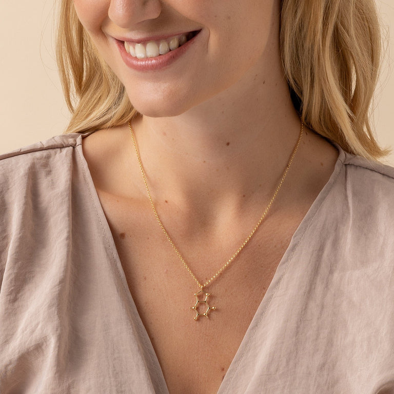 Model showcasing gold vermeil caffeine necklace – scientific chic for coffee lovers. Model showcasing gold vermeil caffeine necklace – scientific chic for coffee lovers.