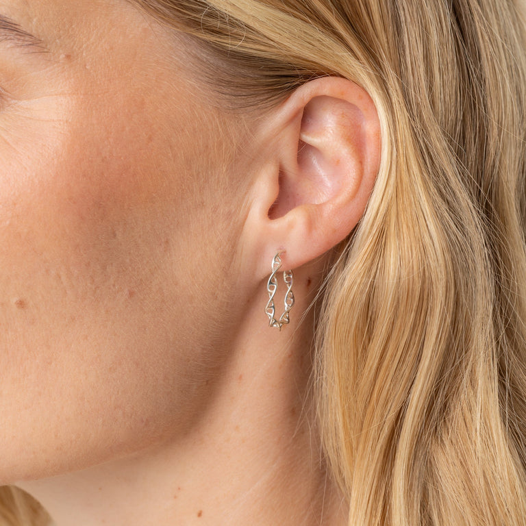 Model wearing DNA Earring Hoops in Silver, showcasing the subtle twist of the DNA double helix. Model wearing DNA Earring Hoops in Silver, showcasing the subtle twist of the DNA double helix.