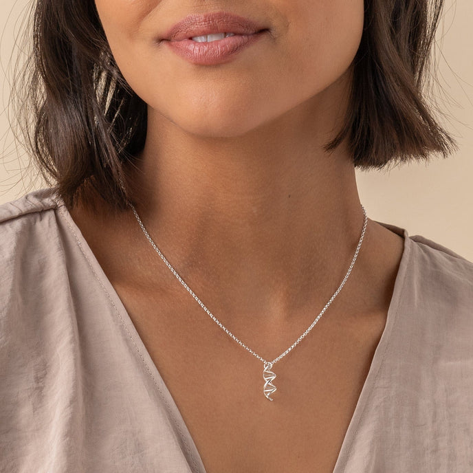 Woman wearing a vertical DNA necklace in sterling silver, perfect for V-necks. Woman wearing a vertical DNA necklace in sterling silver, perfect for V-necks.