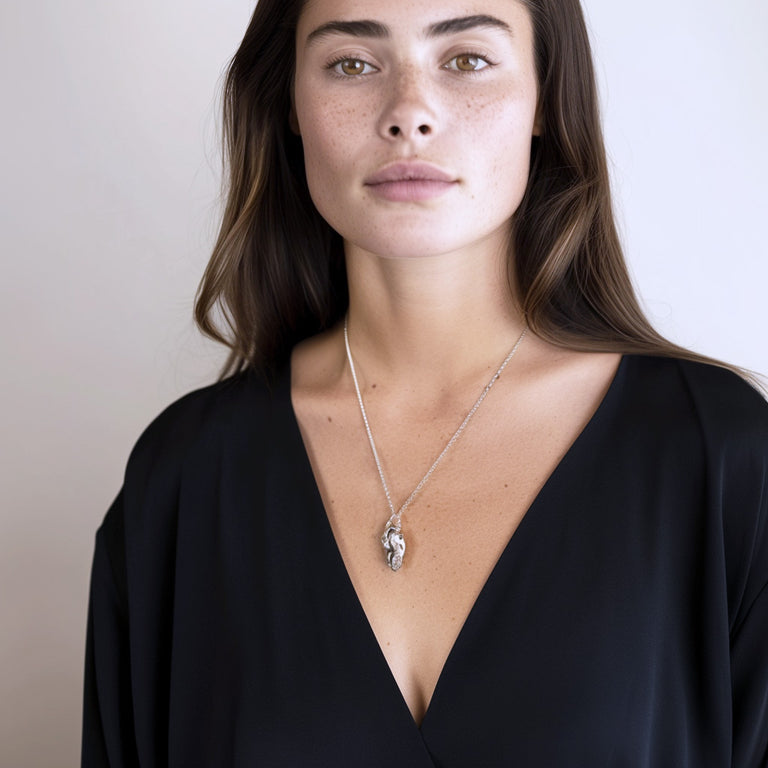 Woman wearing the dog skull necklace with a black v-neck blouse, demonstrating the necklace’s anatomical detail and stylish length. Woman wearing the dog skull necklace with a black v-neck blouse, demonstrating the necklace’s anatomical detail and stylish length.