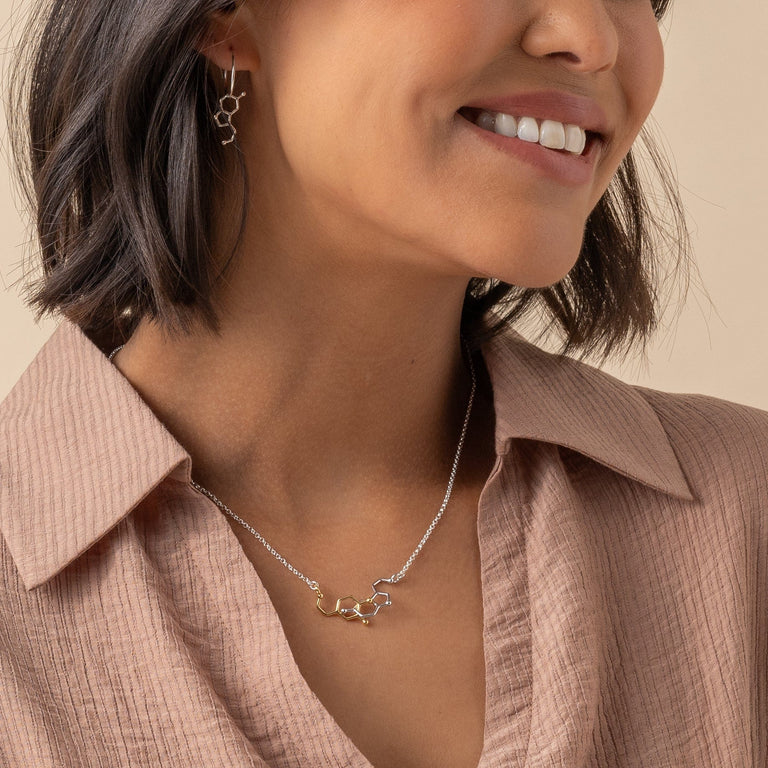 Dopamine-serotonin interlocked necklace showcasing intricate molecular design in silver and gold. Dopamine-serotonin interlocked necklace showcasing intricate molecular design in silver and gold.