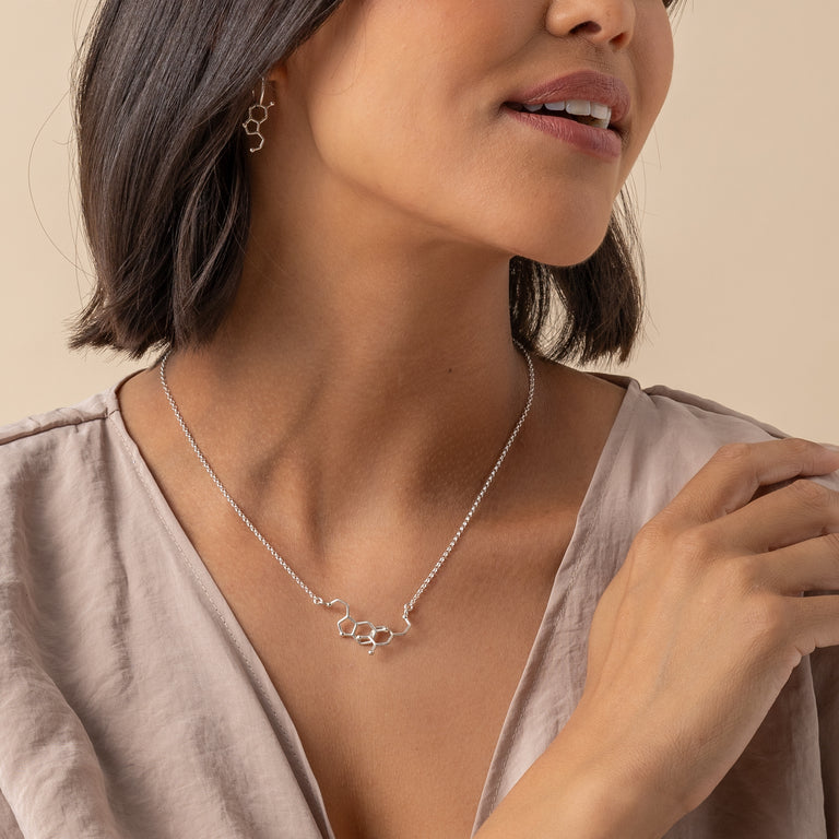 Dopamine & Serotonin Necklace on model, expressing joy and connection through science-inspired jewelry. Dopamine & Serotonin Necklace on model, expressing joy and connection through science-inspired jewelry.