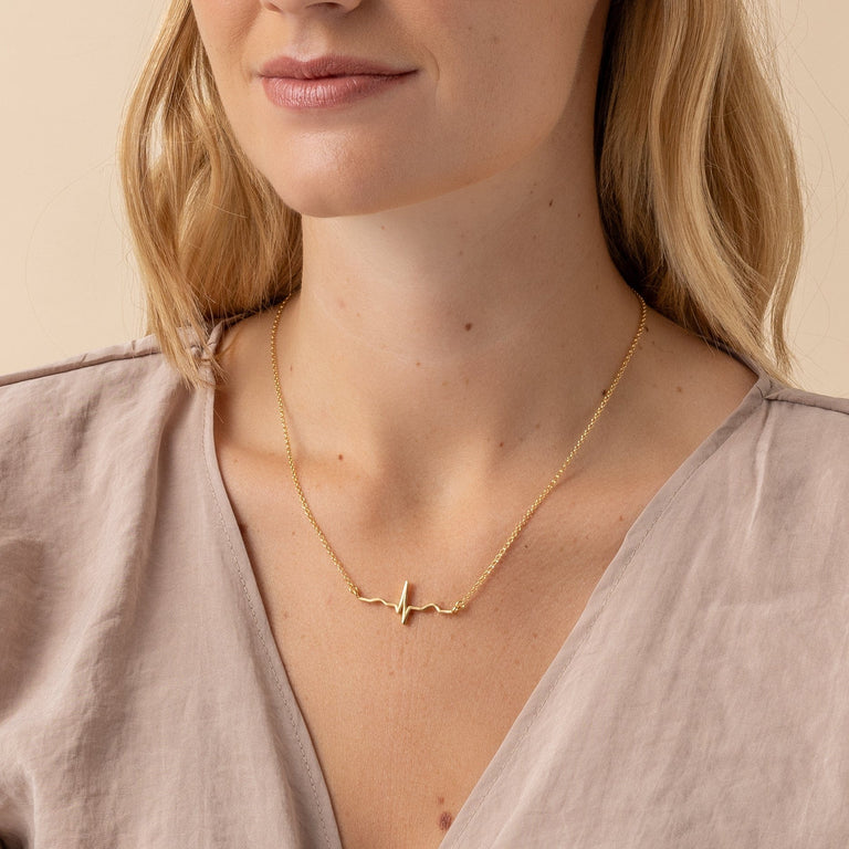 Elegant Vermeil Gold Heartbeat Necklace displayed on a model, perfect for science enthusiasts. Elegant Vermeil Gold Heartbeat Necklace displayed on a model, perfect for science enthusiasts.