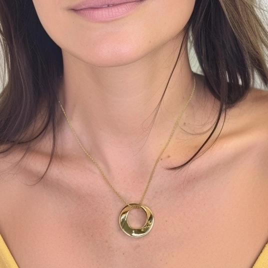 Close-up view of a woman wearing the gold vermeil Möbius strip necklace, highlighting its reflective finish and elegant curvature. Close-up view of a woman wearing the gold vermeil Möbius strip necklace, highlighting its reflective finish and elegant curvature.