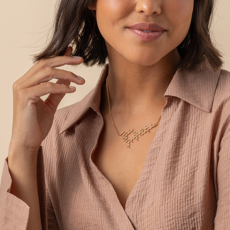 Side view of the Oxytocin Necklace on a model, showcasing the intricate gold vermeil craftsmanship. Side view of the Oxytocin Necklace on a model, showcasing the intricate gold vermeil craftsmanship.