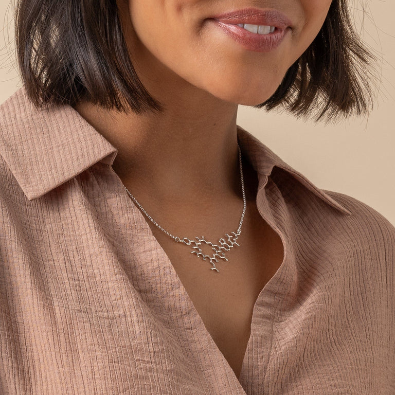 Close-up of oxytocin necklace on the model, emphasizing its elegant connection theme. Close-up of oxytocin necklace on the model, emphasizing its elegant connection theme.