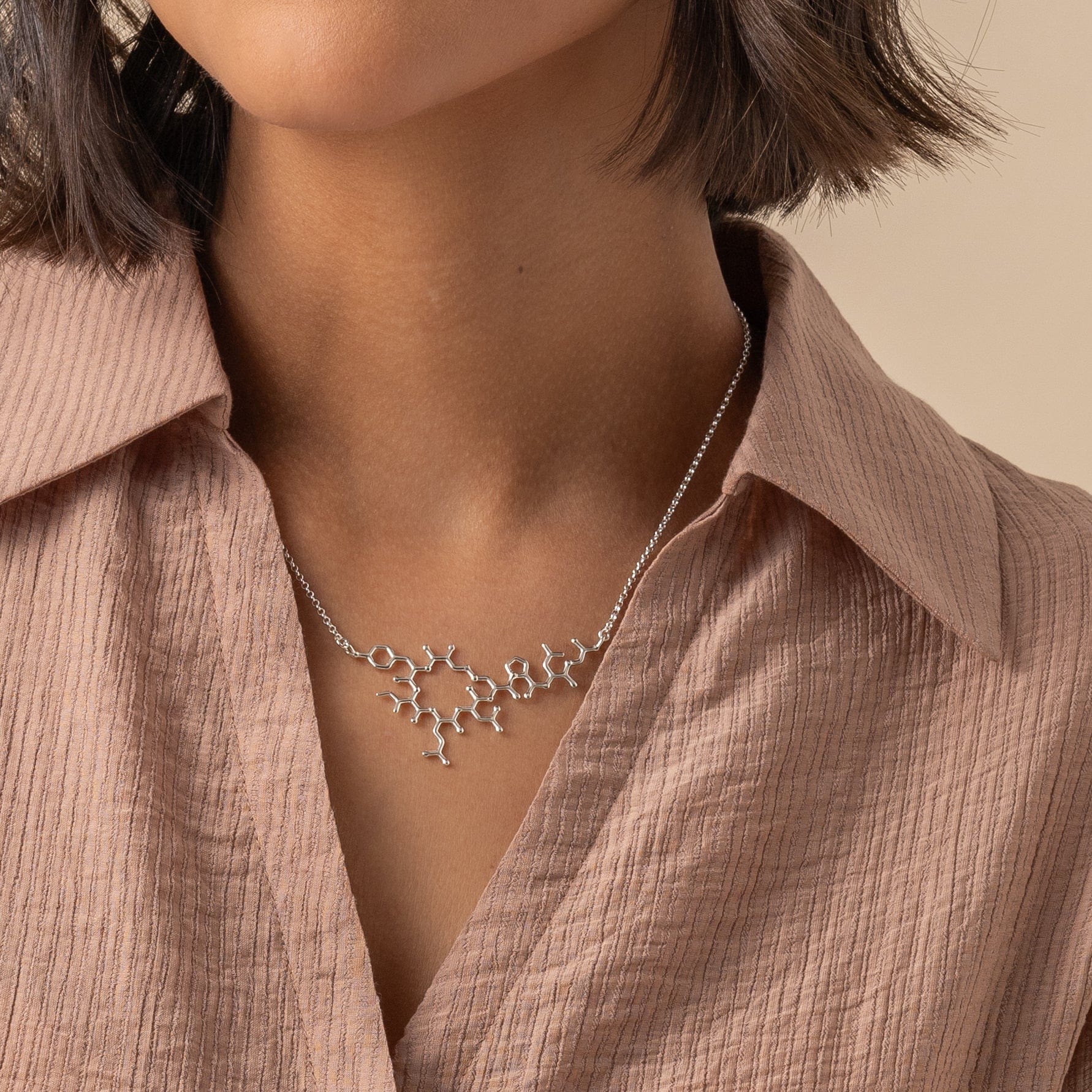 Model wearing the oxytocin necklace, highlighting the sleek and flat design perfect for everyday wear. Model wearing the oxytocin necklace, highlighting the sleek and flat design perfect for everyday wear.