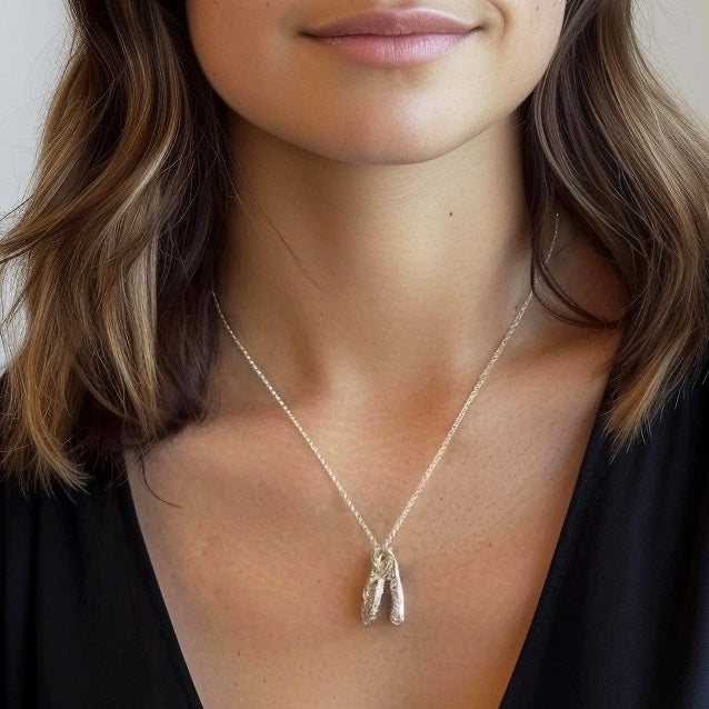 Woman wearing a python skull necklace over a black V-neck top, with a close-up focus on the pendant resting on her chest. Woman wearing a python skull necklace over a black V-neck top, with a close-up focus on the pendant resting on her chest.
