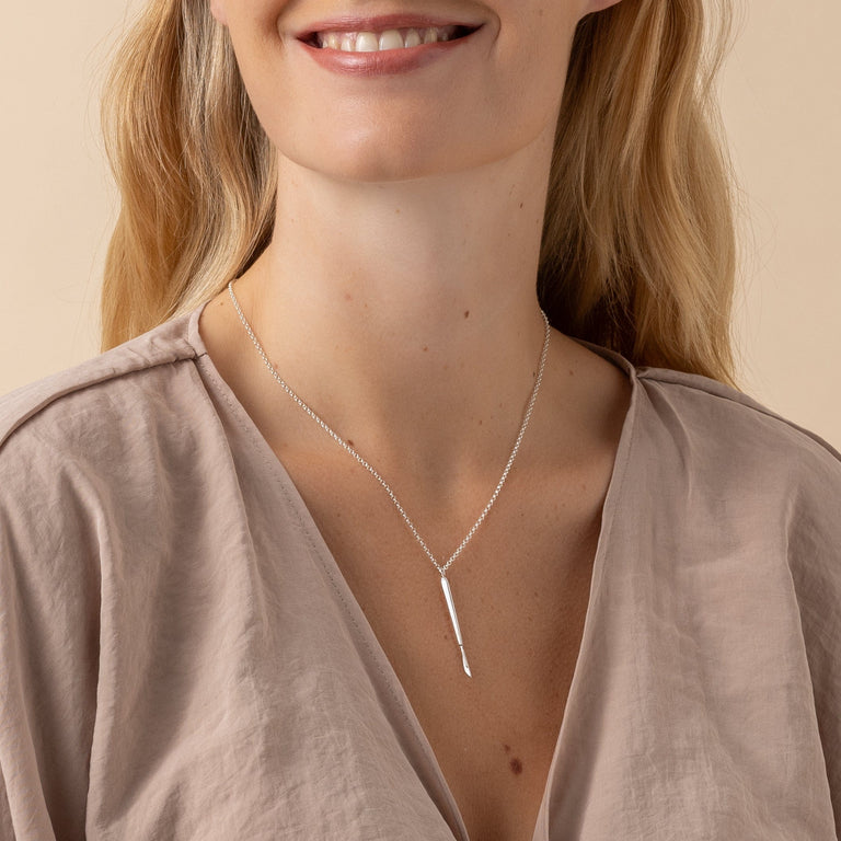 Medical-inspired sterling silver scalpel necklace on model, perfect for science lovers. Medical-inspired sterling silver scalpel necklace on model, perfect for science lovers.