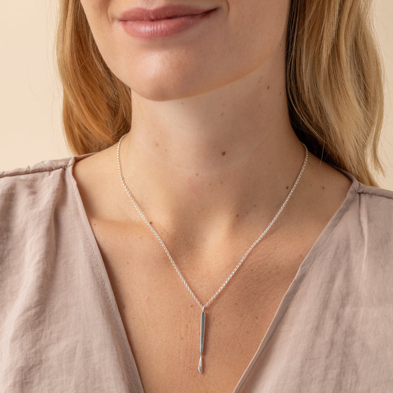 Detailed view of the sterling silver scalpel necklace, capturing its sleek, science-inspired design. Detailed view of the sterling silver scalpel necklace, capturing its sleek, science-inspired design.