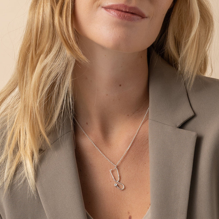 Silver Stethoscope Necklace worn casually, a tribute to the medical field in stylish jewelry form. Silver Stethoscope Necklace worn casually, a tribute to the medical field in stylish jewelry form.
