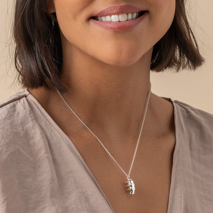 Close-up of a woman wearing the silver tardigrade necklace – a perfect gift for science lovers. Close-up of a woman wearing the silver tardigrade necklace – a perfect gift for science lovers.
