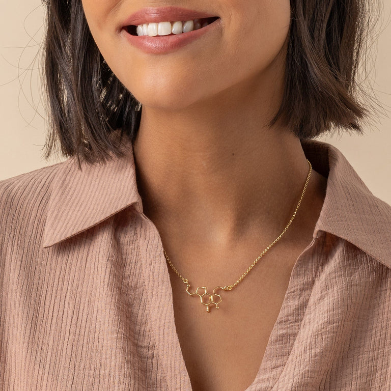Lifestyle shot of dopamine-serotonin necklace in gold vermeil, ideal for those seeking a blend of science and style in their jewelry. Lifestyle shot of dopamine-serotonin necklace in gold vermeil, ideal for those seeking a blend of science and style in their jewelry.