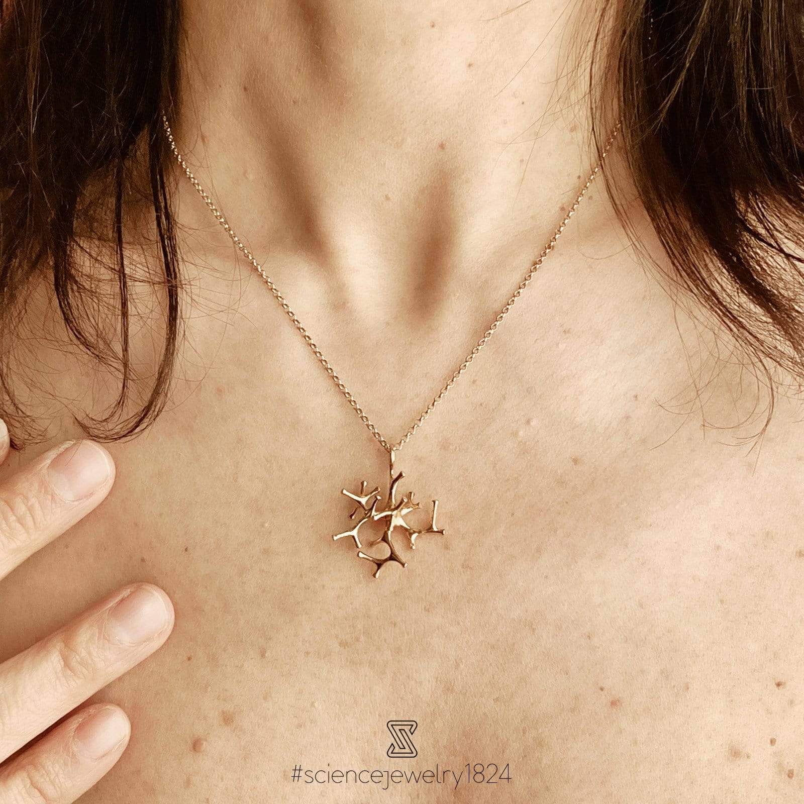 Woman wearing a gold vermeil astrocyte necklace, highlighting its elegant, science-inspired design and luxurious shine. Woman wearing a gold vermeil astrocyte necklace, highlighting its elegant, science-inspired design and luxurious shine.