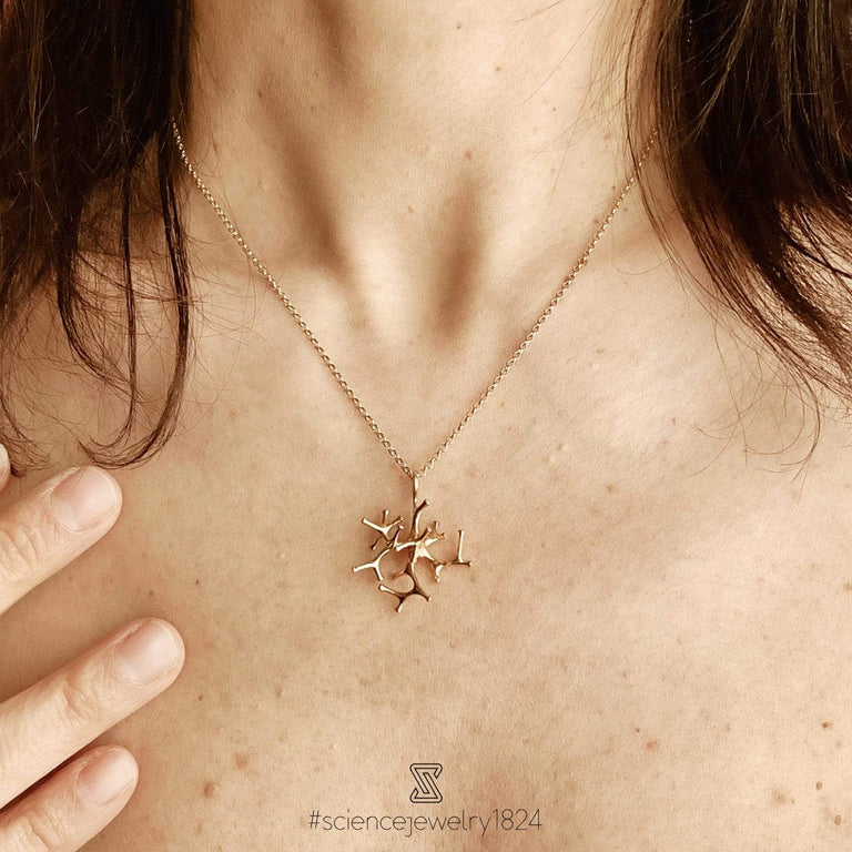 Woman wearing a gold vermeil astrocyte necklace, highlighting its elegant, science-inspired design and luxurious shine. Woman wearing a gold vermeil astrocyte necklace, highlighting its elegant, science-inspired design and luxurious shine.