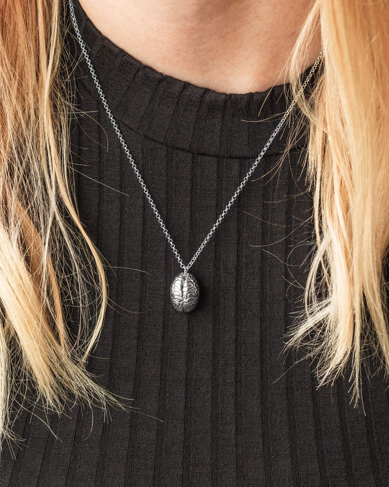 Woman wearing a silver brain necklace, styled for modern and intellectual appeal. Woman wearing a silver brain necklace, styled for modern and intellectual appeal.