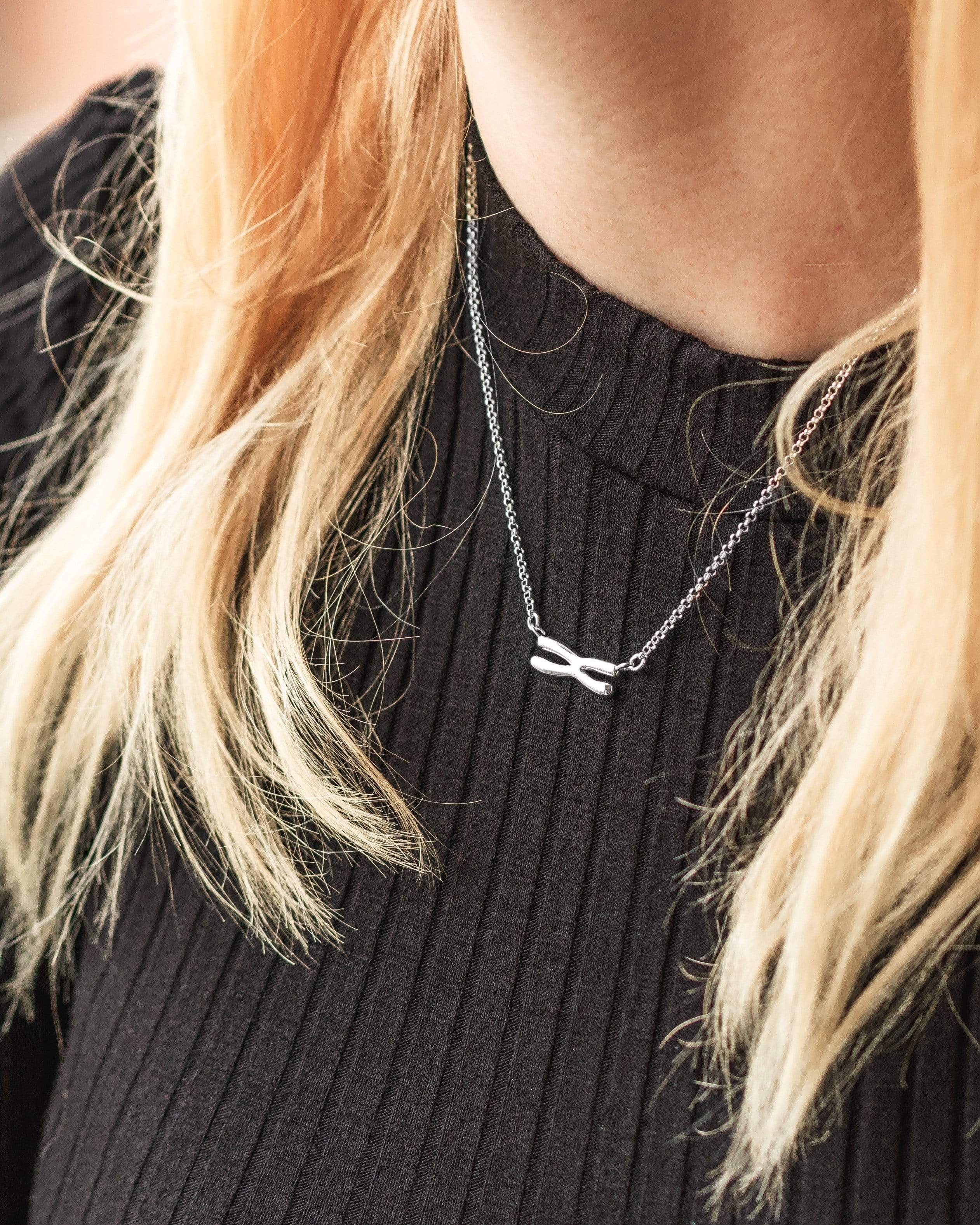 Woman wearing a silver chromosome necklace, a stylish science-inspired accessory. Woman wearing a silver chromosome necklace, a stylish science-inspired accessory.