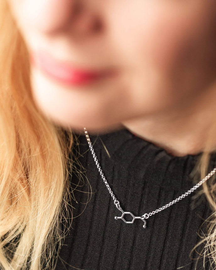 Close-up of a woman wearing the dopamine necklace in sterling silver. Close-up of a woman wearing the dopamine necklace in sterling silver.