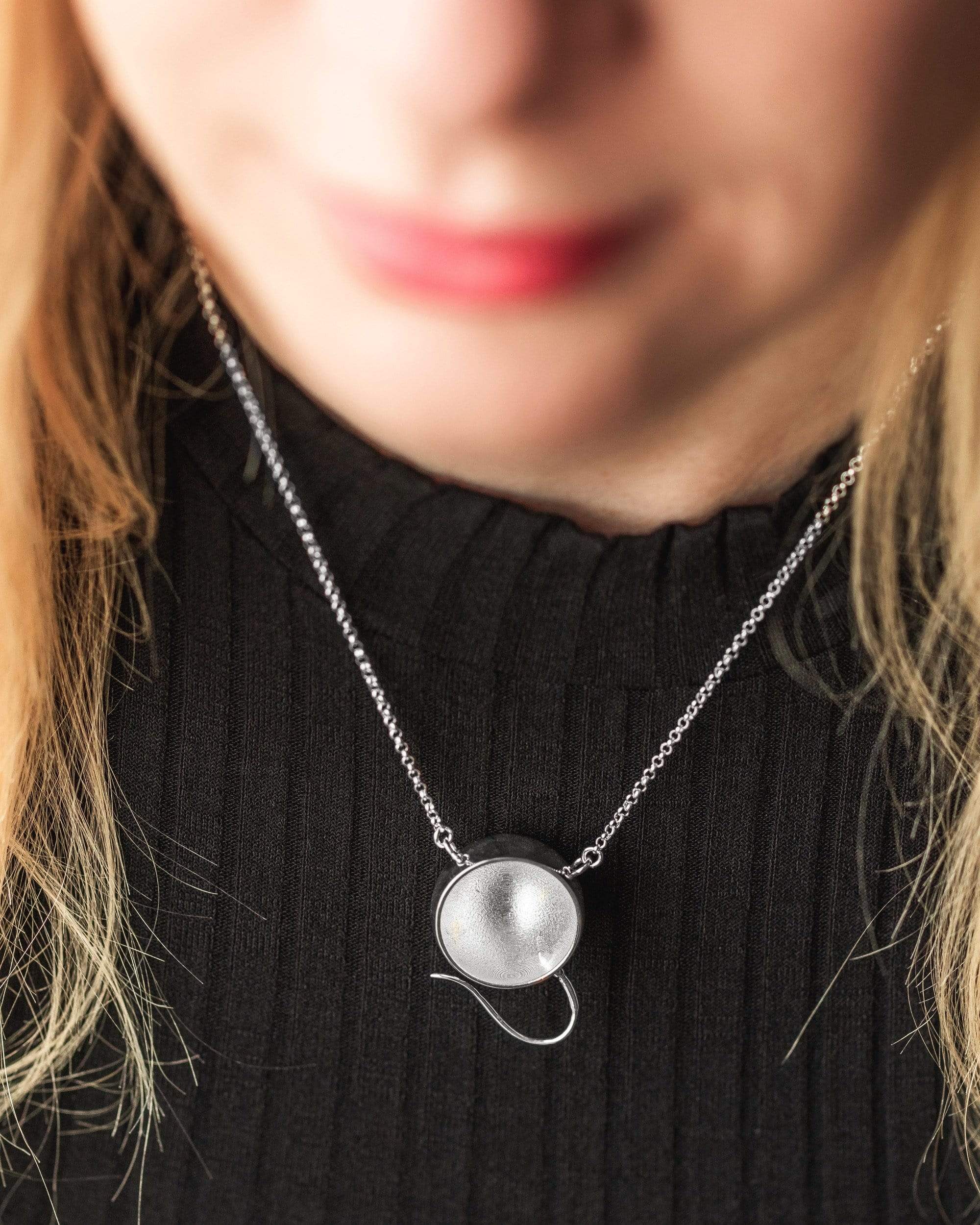 Close-up of a woman wearing an egg and sperm necklace, showcasing its elegant design. Close-up of a woman wearing an egg and sperm necklace, showcasing its elegant design.