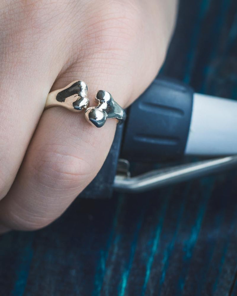 Close-up of a sterling silver femur ring worn on a finger, highlighting its intricate craftsmanship and unique scientific inspiration. Close-up of a sterling silver femur ring worn on a finger, highlighting its intricate craftsmanship and unique scientific inspiration.