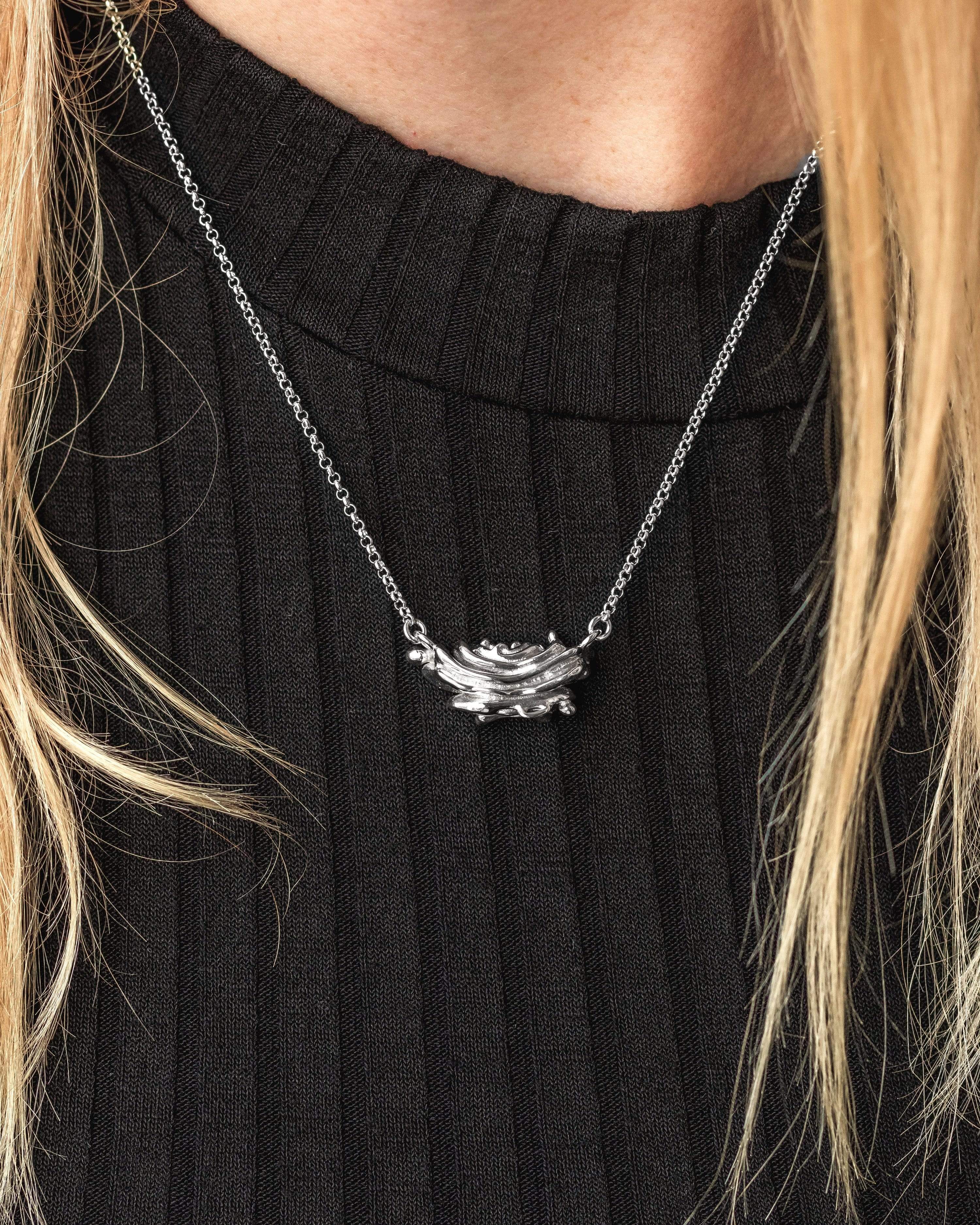 Woman wearing the Golgi necklace, highlighting its elegant and minimalist scientific aesthetic. Woman wearing the Golgi necklace, highlighting its elegant and minimalist scientific aesthetic.