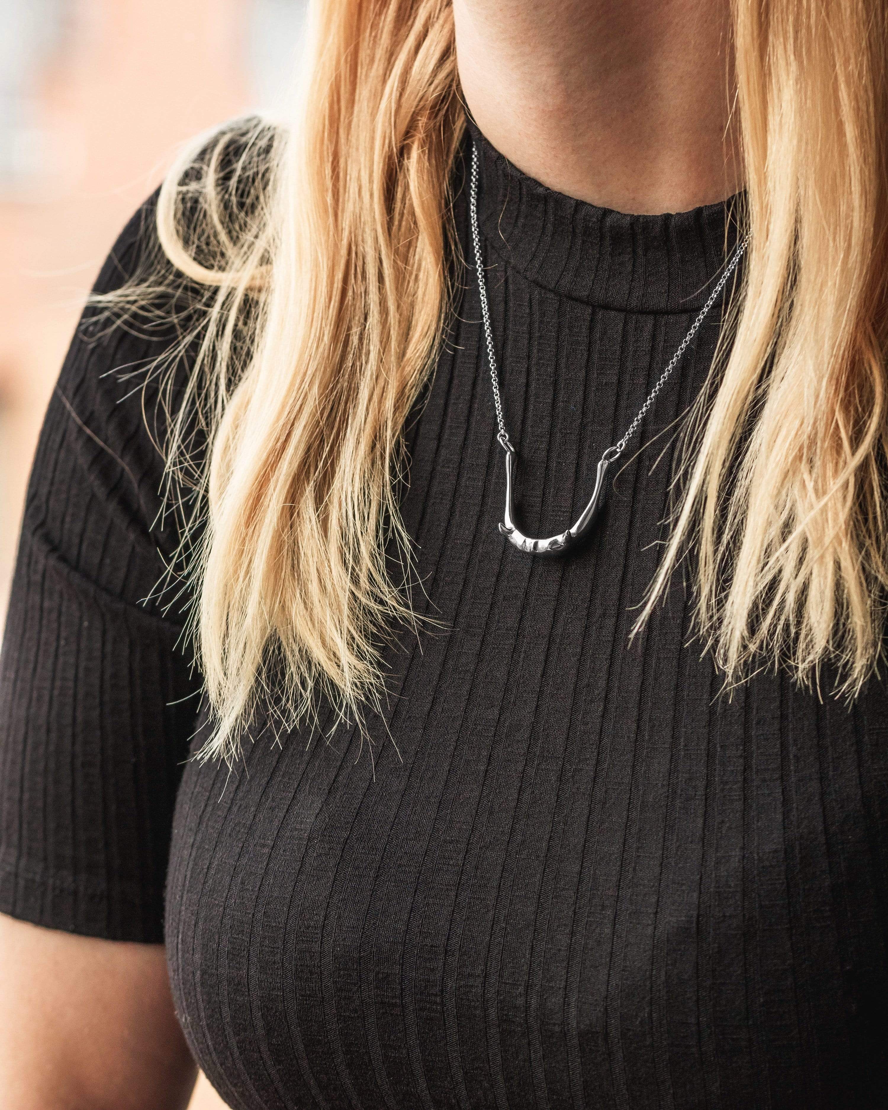 Close-up of silver hyoid bone necklace, highlighting anatomical precision and elegant craftsmanship. Close-up of silver hyoid bone necklace, highlighting anatomical precision and elegant craftsmanship.