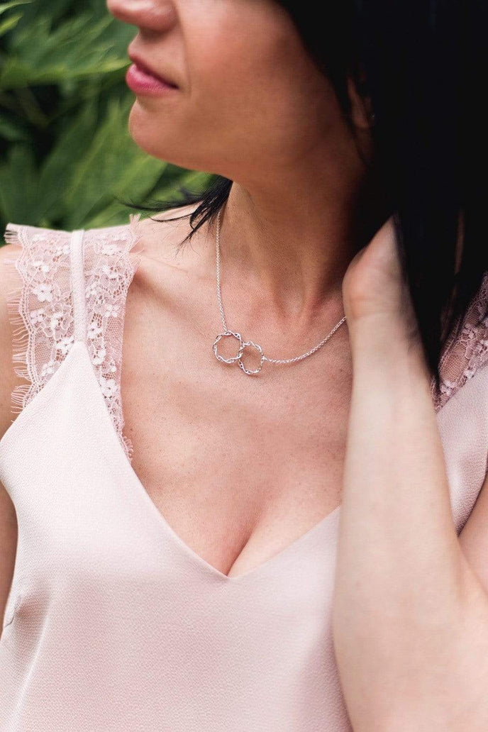 Model wearing the interlocking DNA necklace, showcasing the elegant silver double helix design. Model wearing the interlocking DNA necklace, showcasing the elegant silver double helix design.