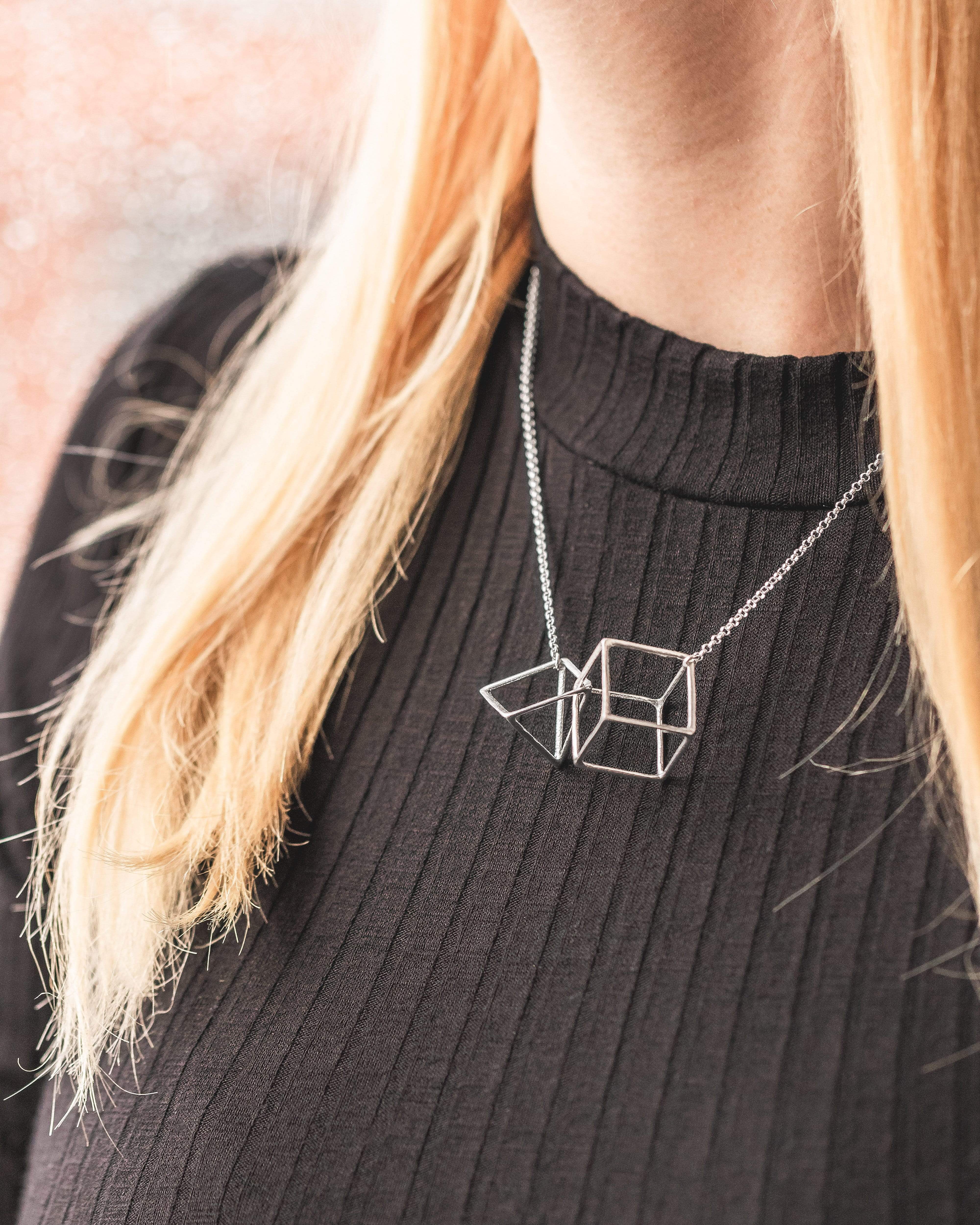 Silver interlocked geometry necklace styled on a model, showcasing its elegance and simplicity. Silver interlocked geometry necklace styled on a model, showcasing its elegance and simplicity.