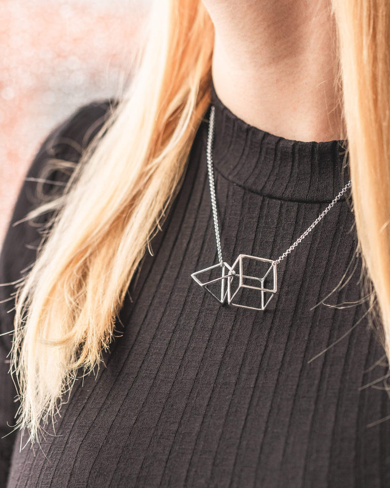Silver interlocked geometry necklace styled on a model, showcasing its elegance and simplicity. Silver interlocked geometry necklace styled on a model, showcasing its elegance and simplicity.