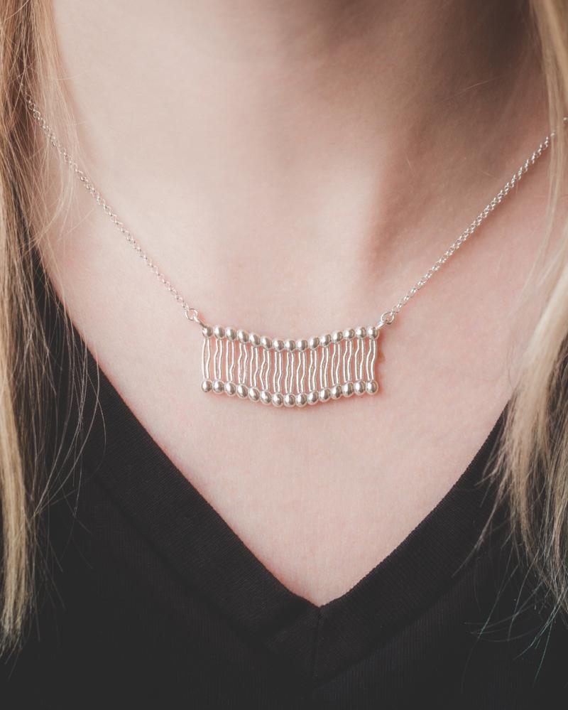 Model wearing a sterling silver membrane necklace, showcasing its elegant scientific design. Model wearing a sterling silver membrane necklace, showcasing its elegant scientific design.
