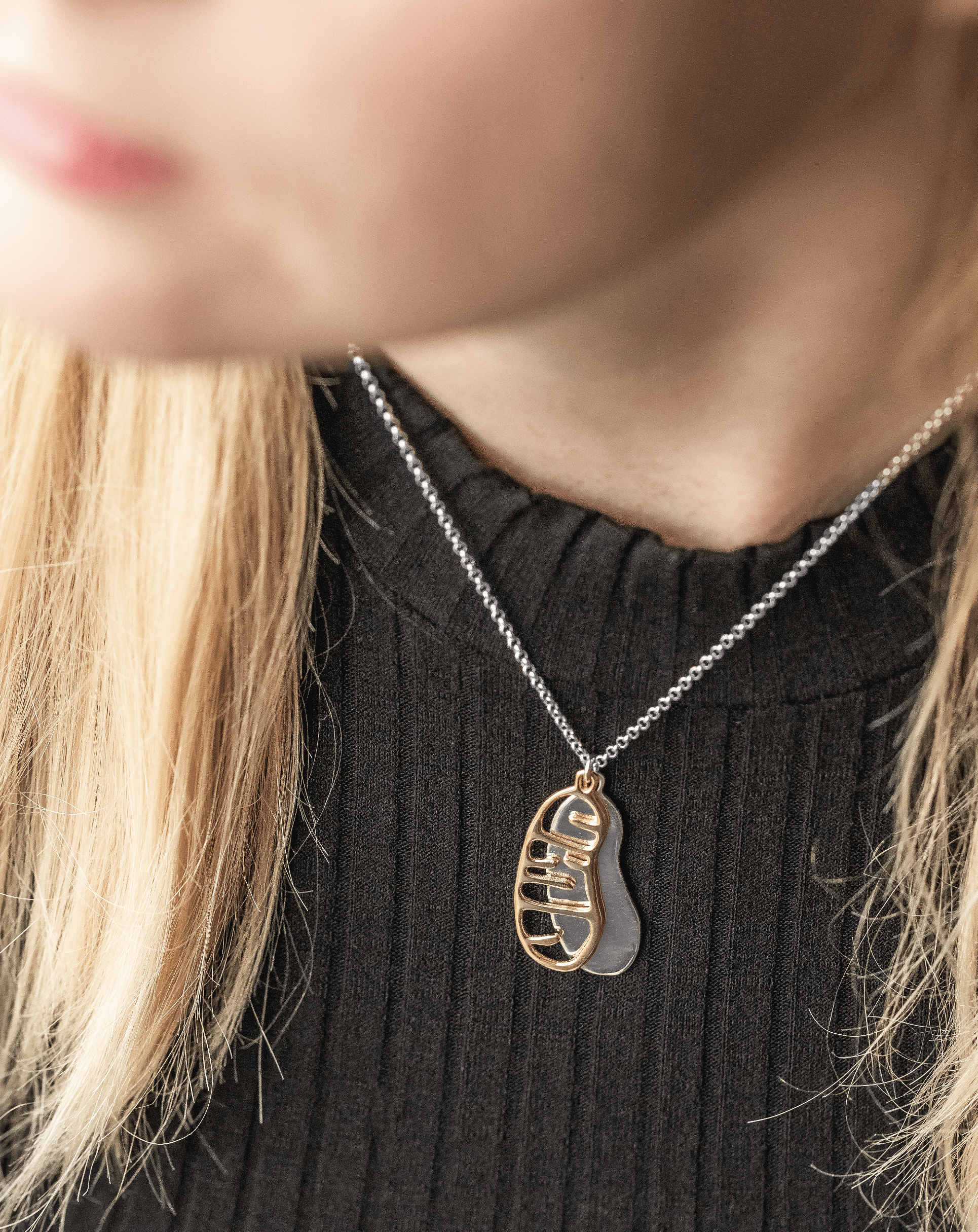 Model wearing mitochondrion necklace with silver-gold contrast, stylish science jewelry gift idea. Model wearing mitochondrion necklace with silver-gold contrast, stylish science jewelry gift idea.