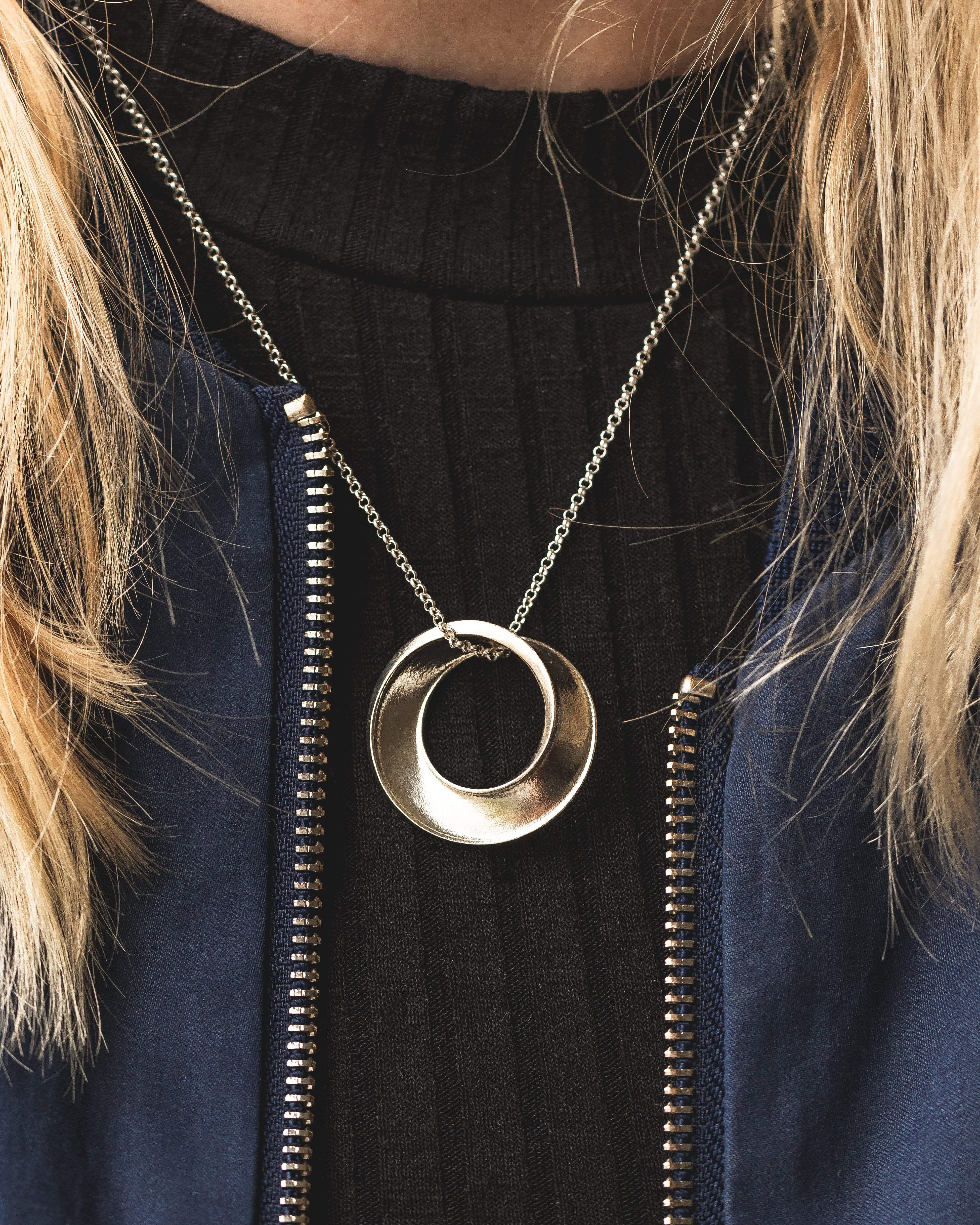 Close-up view of silver Möbius strip necklace, showcasing intricate one-sided surface detail. Close-up view of silver Möbius strip necklace, showcasing intricate one-sided surface detail.
