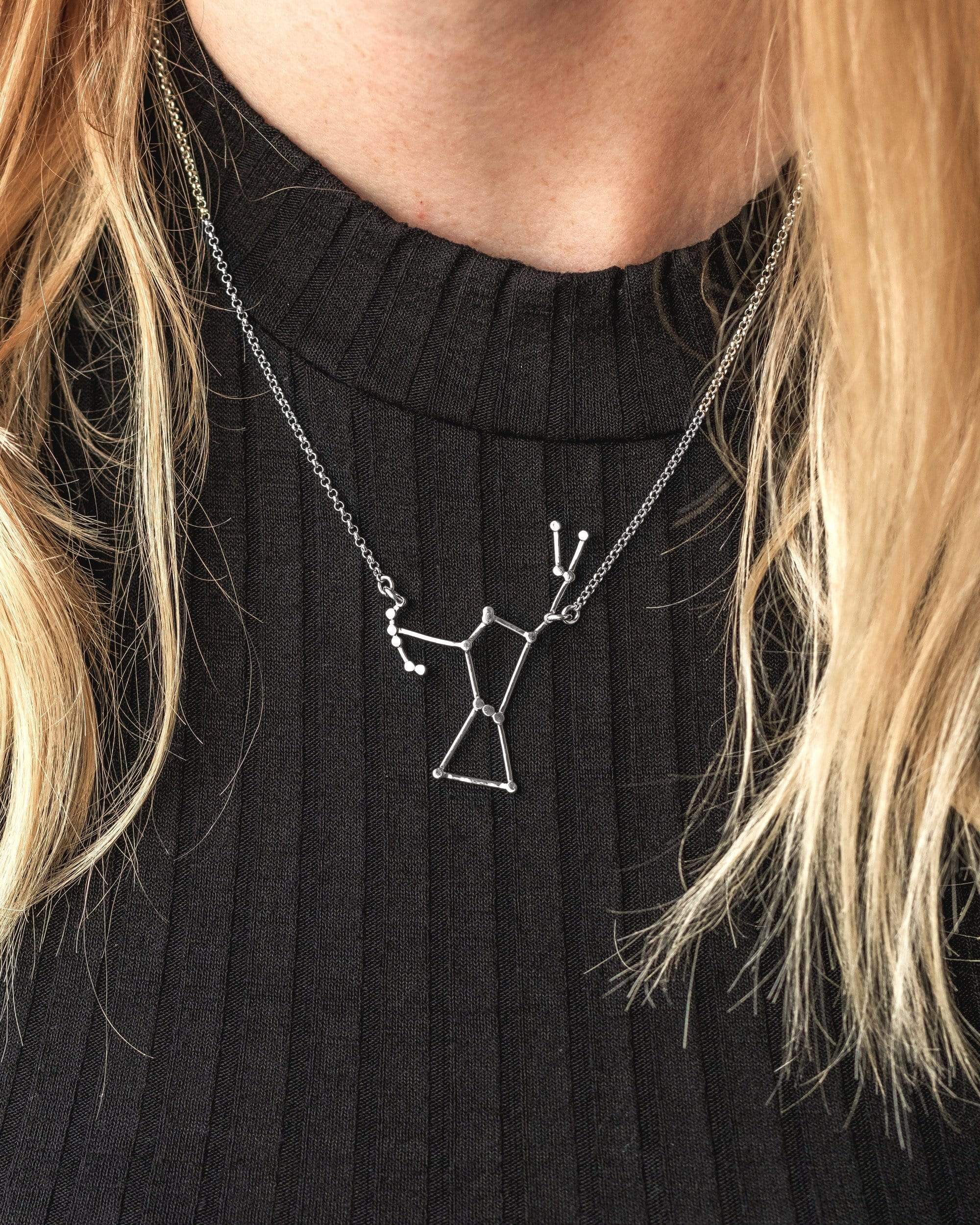 Woman wearing the silver Orion Necklace showcasing its constellation design. Woman wearing the silver Orion Necklace showcasing its constellation design.