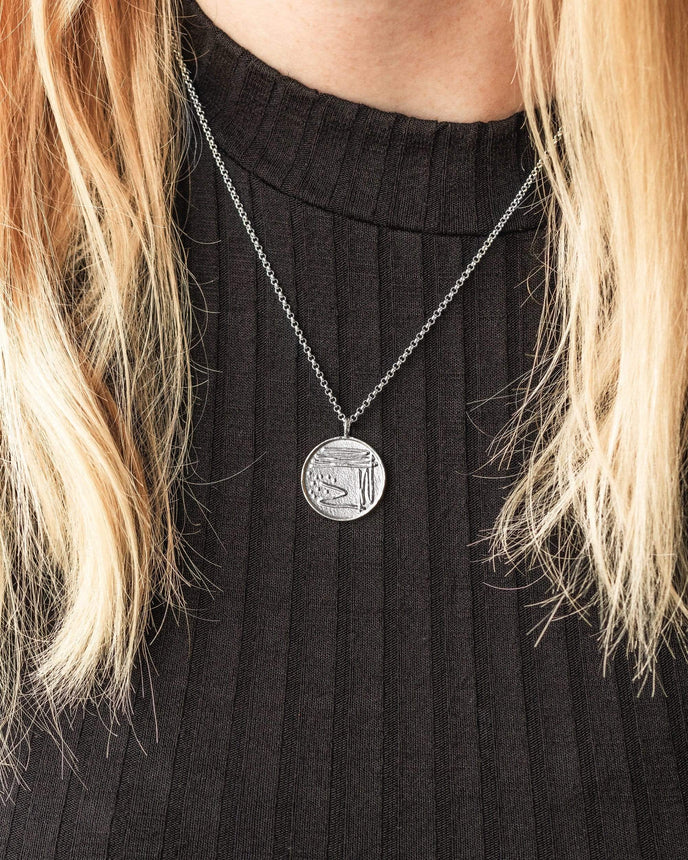 Close-up of the Petri Dish Necklace in sterling silver on a model, inspired by microbiology. Close-up of the Petri Dish Necklace in sterling silver on a model, inspired by microbiology.