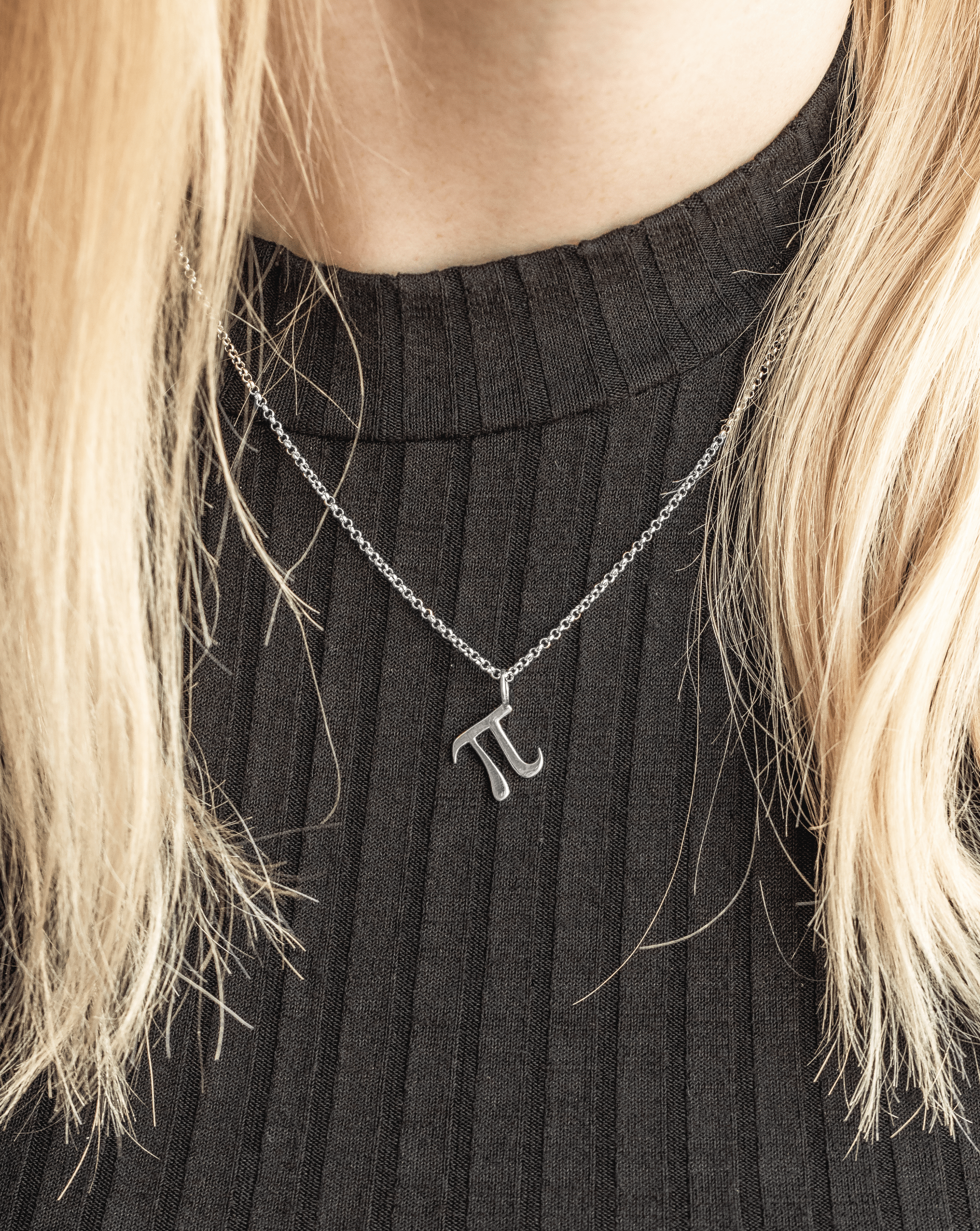 Woman wearing a minimalist sterling silver pi necklace, styled elegantly with a casual outfit. Woman wearing a minimalist sterling silver pi necklace, styled elegantly with a casual outfit.