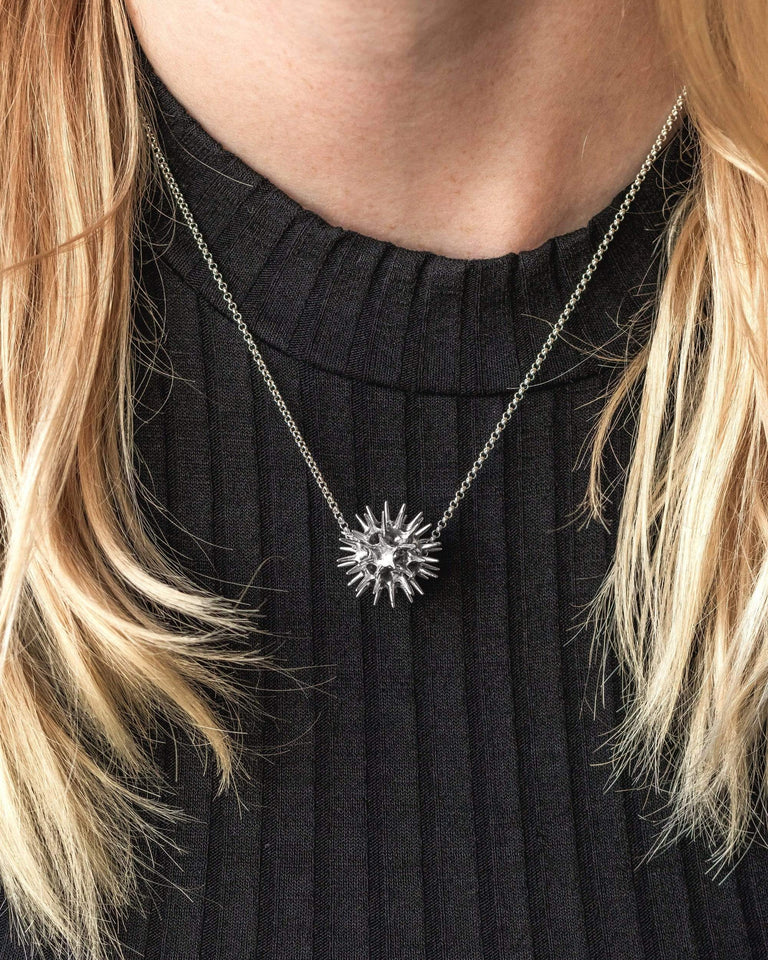 Model wearing the pollen grain necklace in silver, highlighting its delicate and scientific design. Model wearing the pollen grain necklace in silver, highlighting its delicate and scientific design.