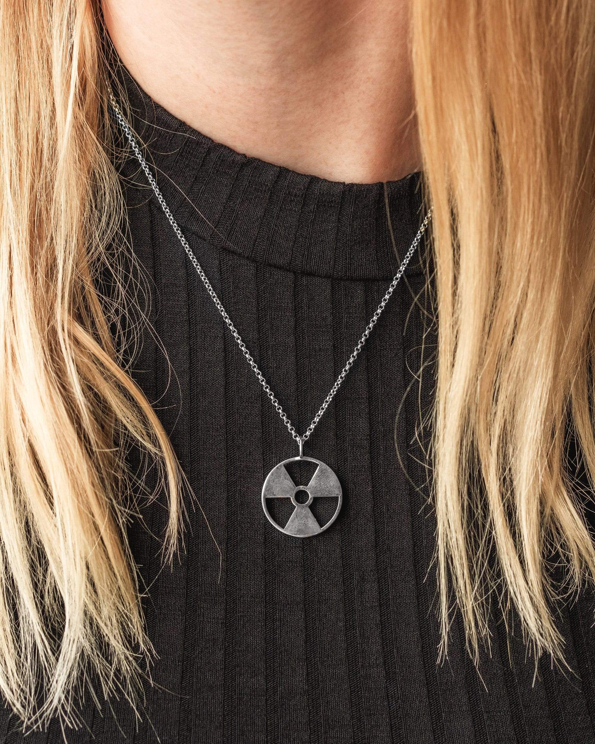 Close-up view of silver radiation symbol necklace, emphasizing its unique design and craftsmanship. Close-up view of silver radiation symbol necklace, emphasizing its unique design and craftsmanship.