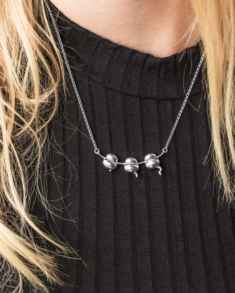Person wearing the Ribosomes Necklace in silver, displaying the necklace’s chic and unique science-inspired design. Person wearing the Ribosomes Necklace in silver, displaying the necklace’s chic and unique science-inspired design.