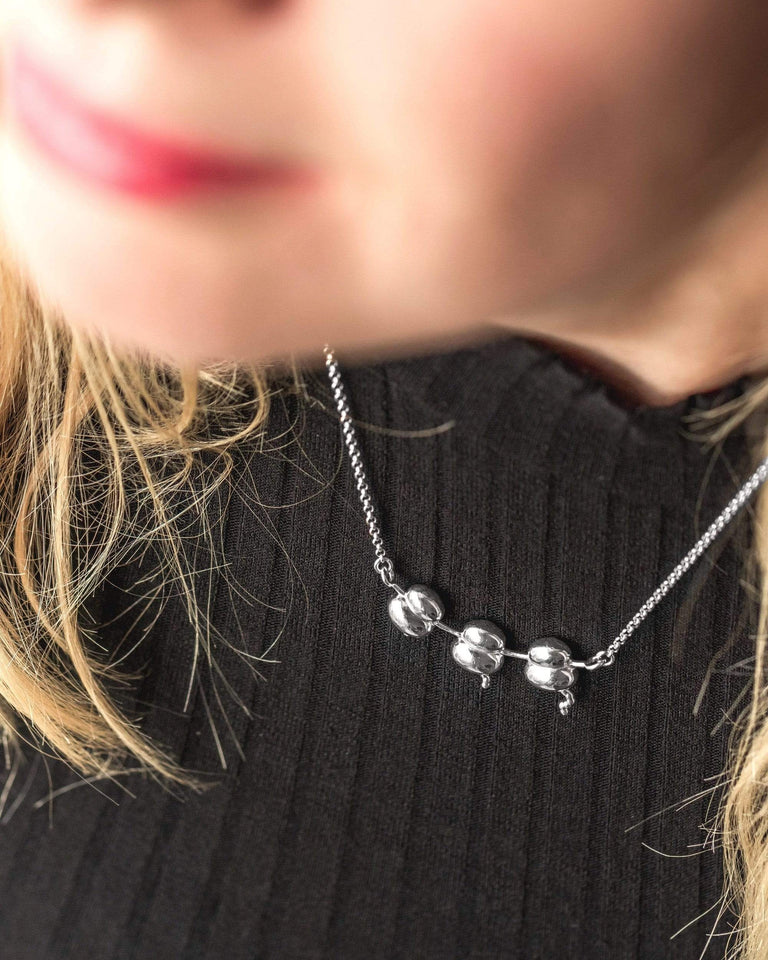 Close-up of Ribosomes Necklace worn around the neck, highlighting the silver pendant’s scientific inspiration and detailed craftsmanship. Close-up of Ribosomes Necklace worn around the neck, highlighting the silver pendant’s scientific inspiration and detailed craftsmanship.
