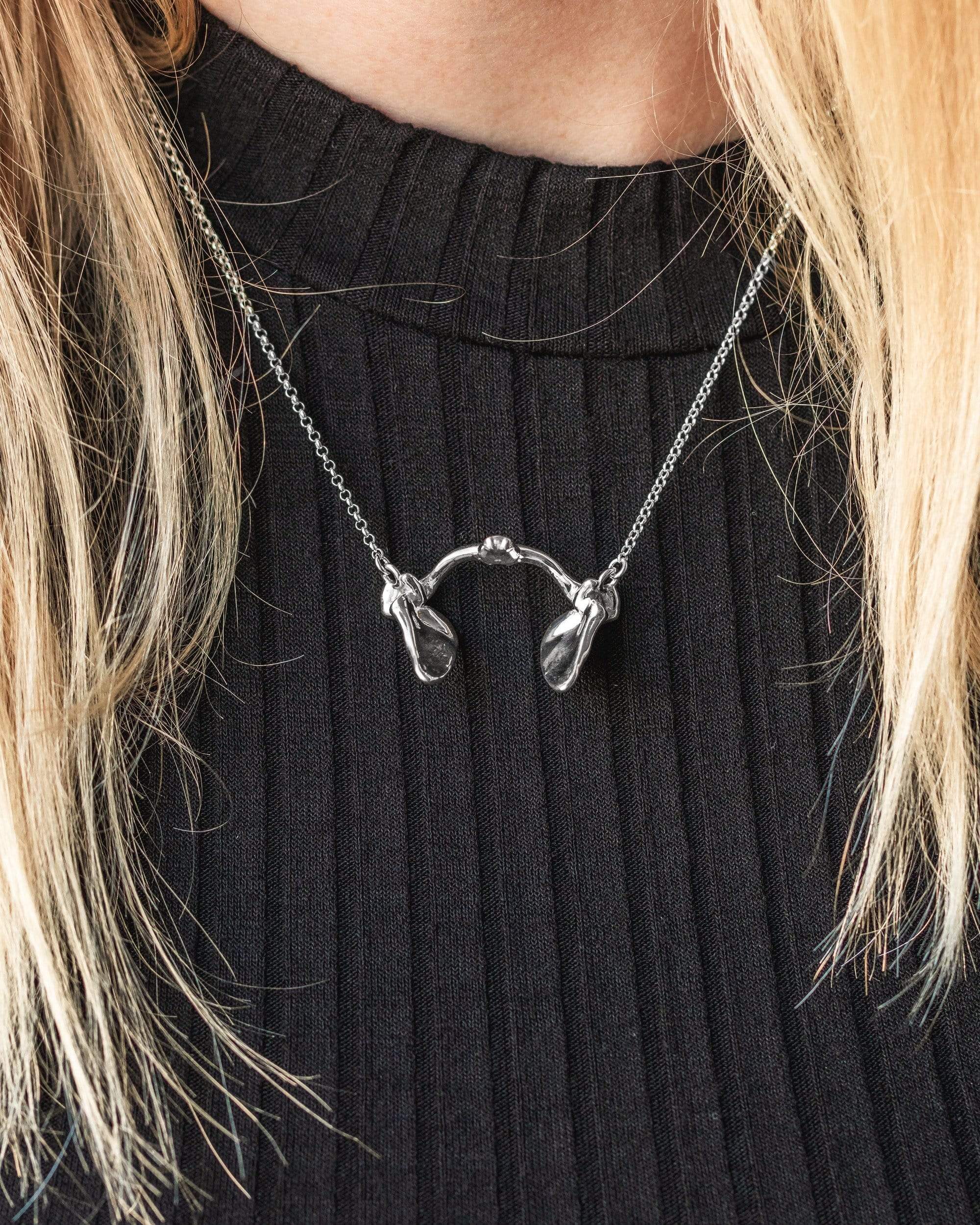 A model wearing the scapula necklace over a black top, showcasing its anatomical detail and elegant design. A model wearing the scapula necklace over a black top, showcasing its anatomical detail and elegant design.