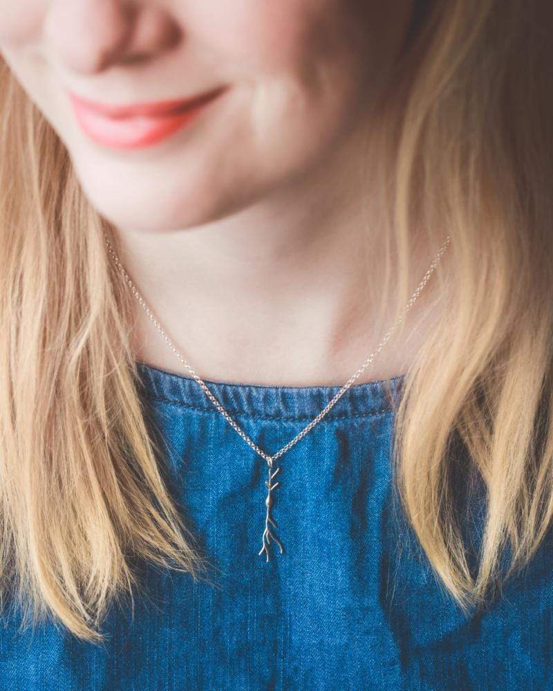 Model wearing a silver spindle neuron necklace, highlighting its minimalist elegance. Model wearing a silver spindle neuron necklace, highlighting its minimalist elegance.