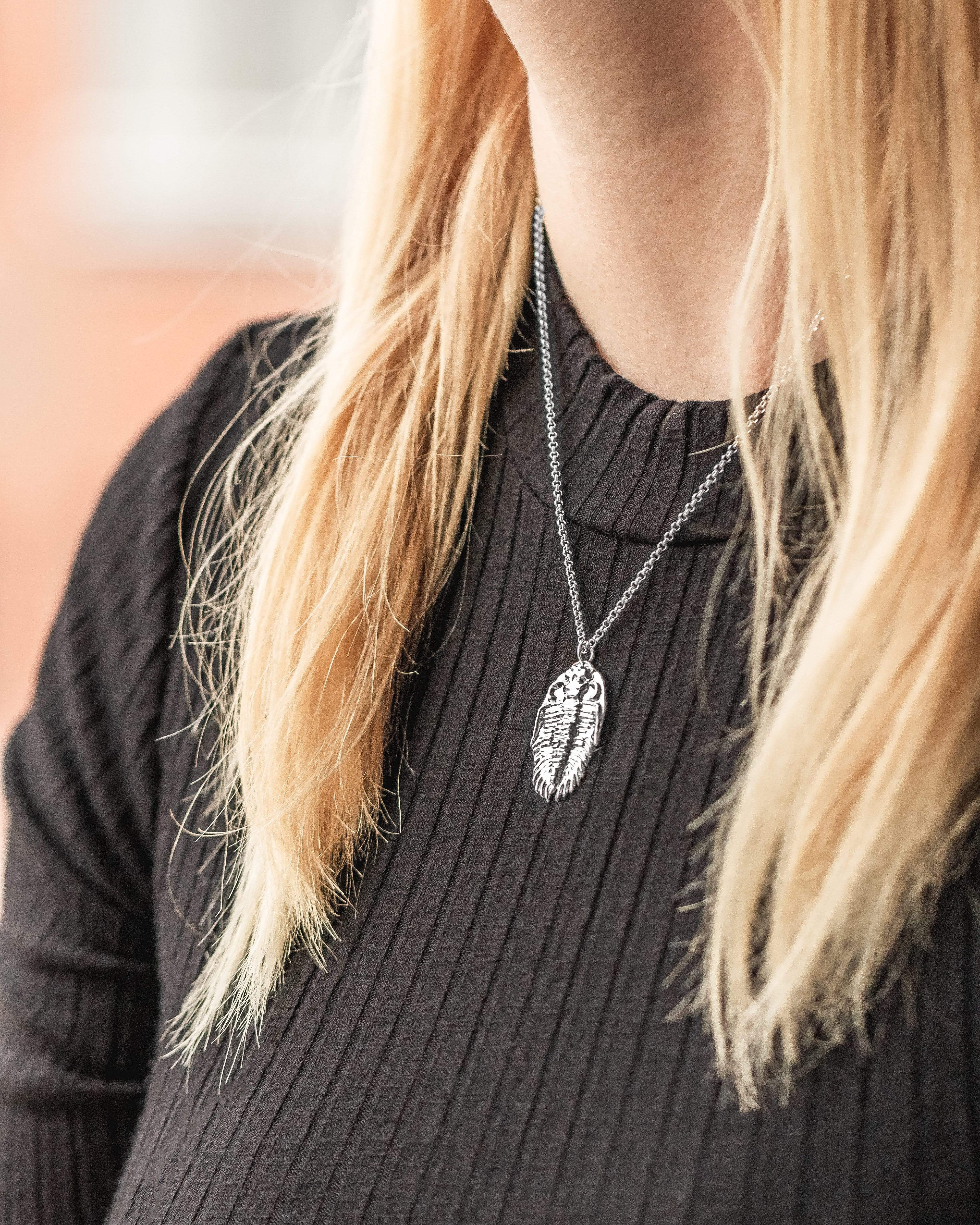 A model wearing the trilobite necklace, showcasing its elegant and unique design. A model wearing the trilobite necklace, showcasing its elegant and unique design.